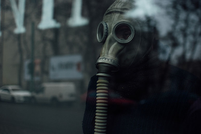 Crime scene technician wearing a respirator standing behind the glass