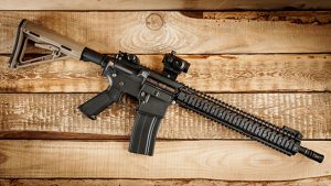 A Black AR-15 Assault Rifle Against a Wooden Table